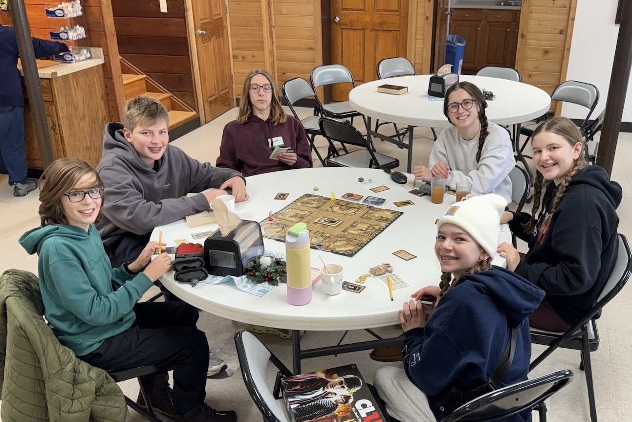 Group of smiling pre-teens playing a board game. 