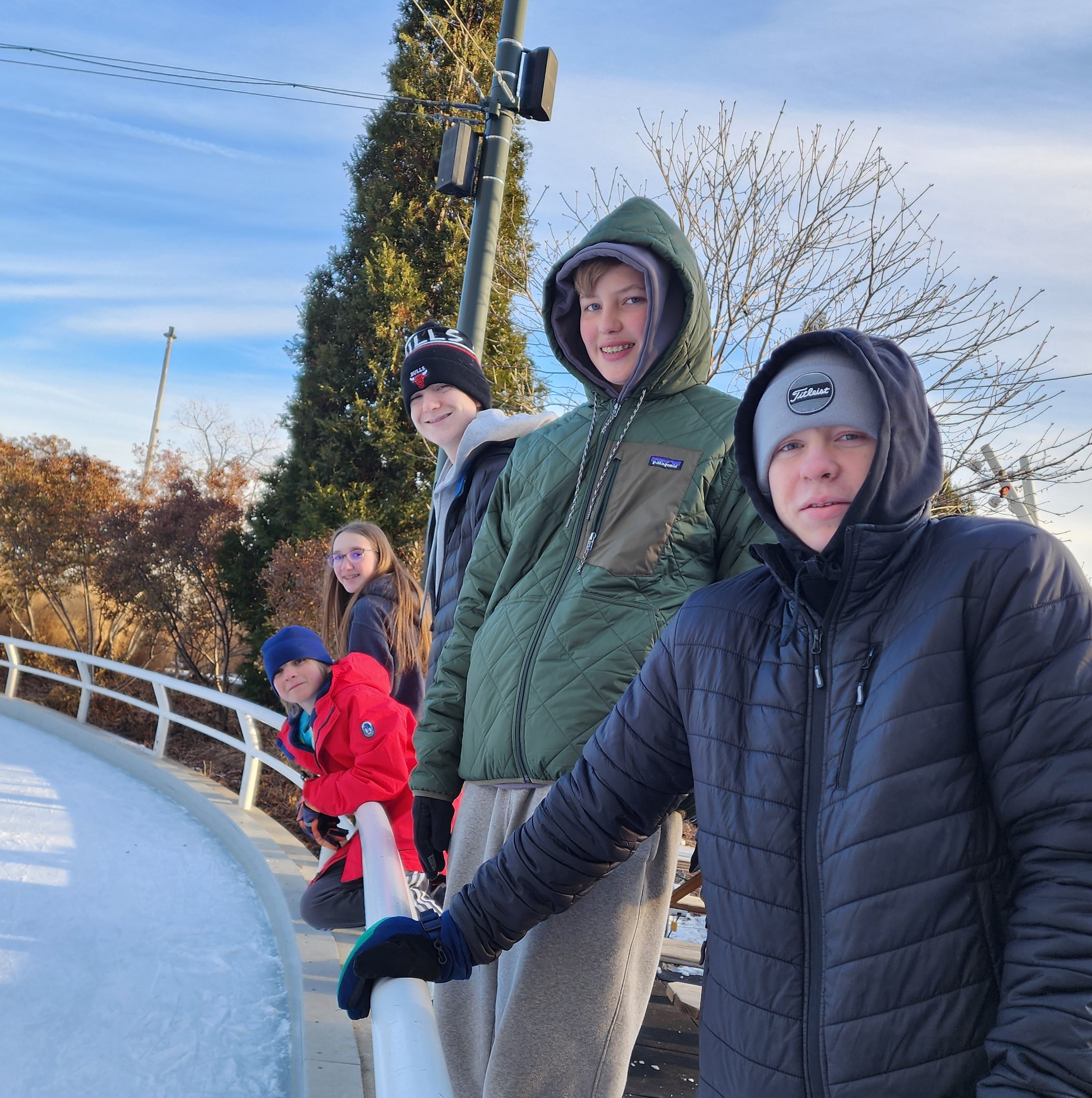 Group of teens at an outdoor ice skating rink. 