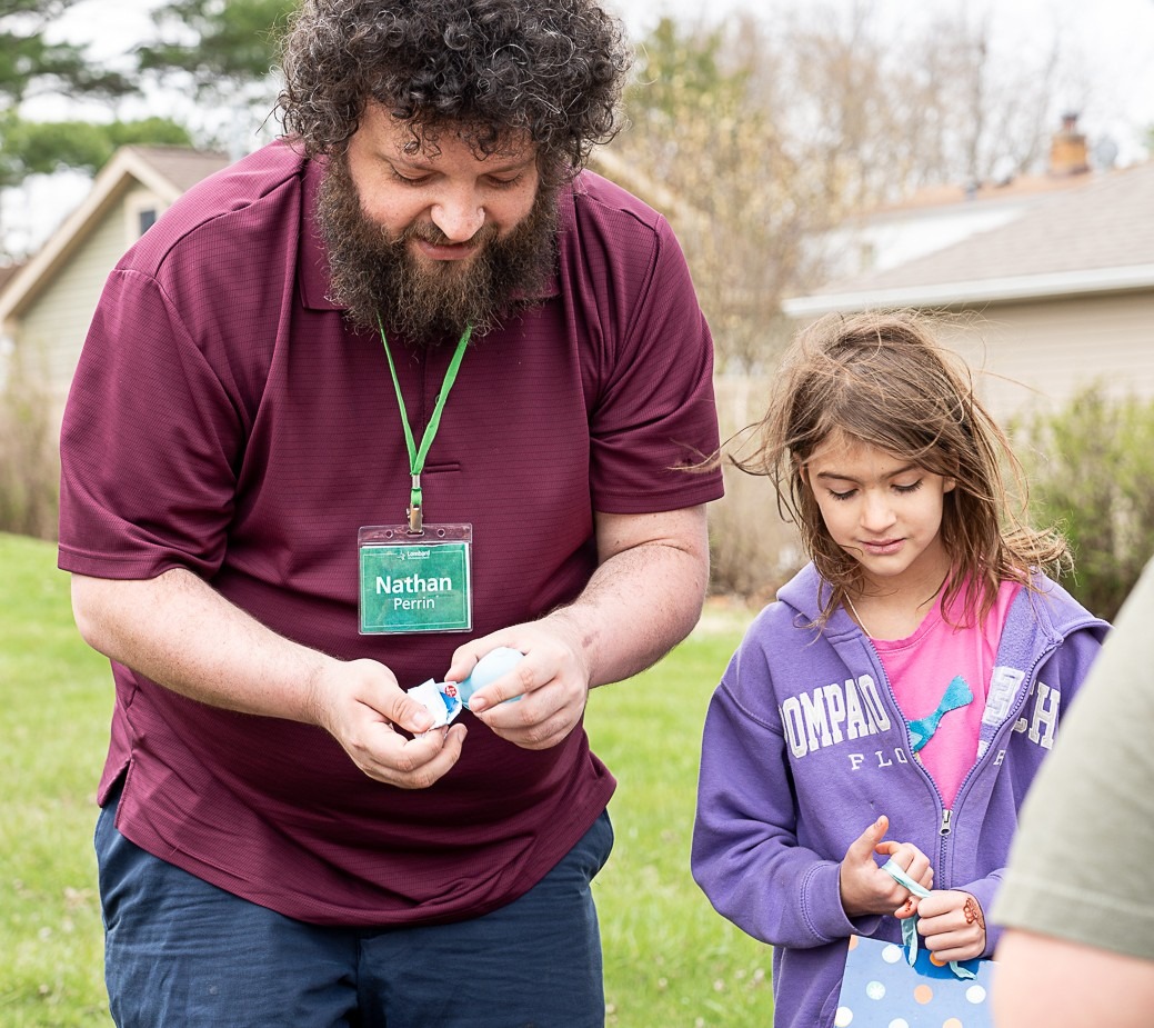 Man and young girl with plastic Easter eggs outside on a church lawn