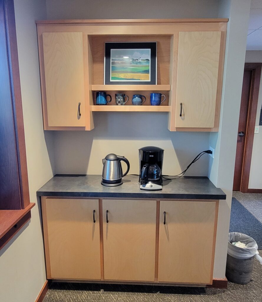 An attractive small cabinet set with coffee mugs and art.