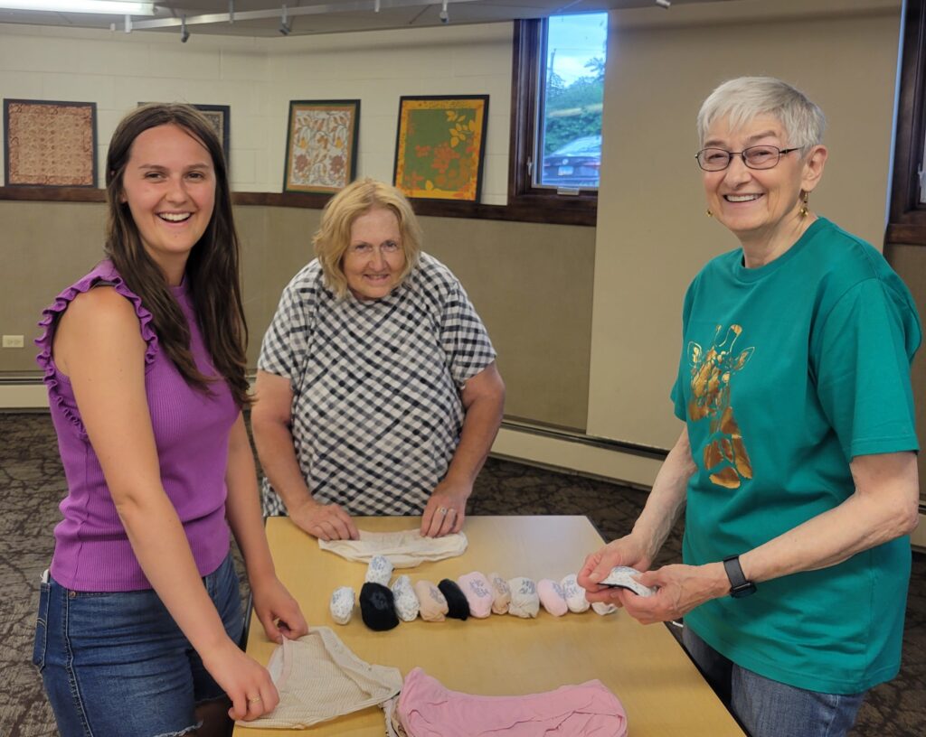 Three women roll panties inside a church fellowship hall. 