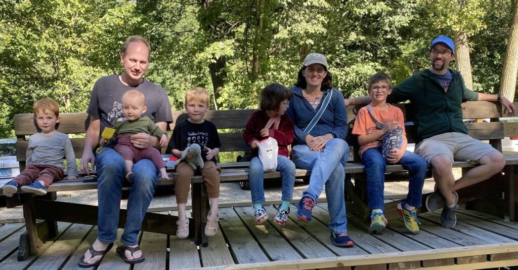 Two families with young children enjoy a hayrack ride at a camp. 