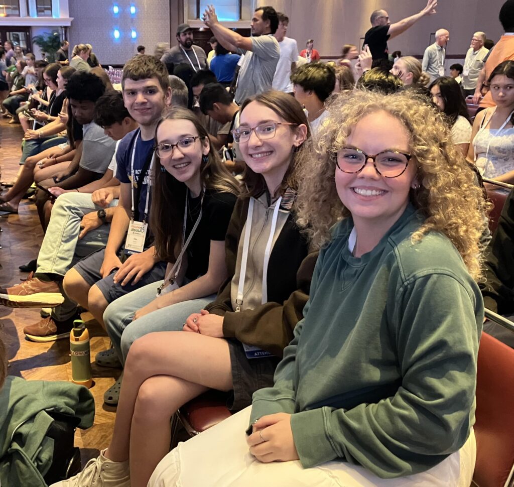 Four teens smiling inside a convention center. 