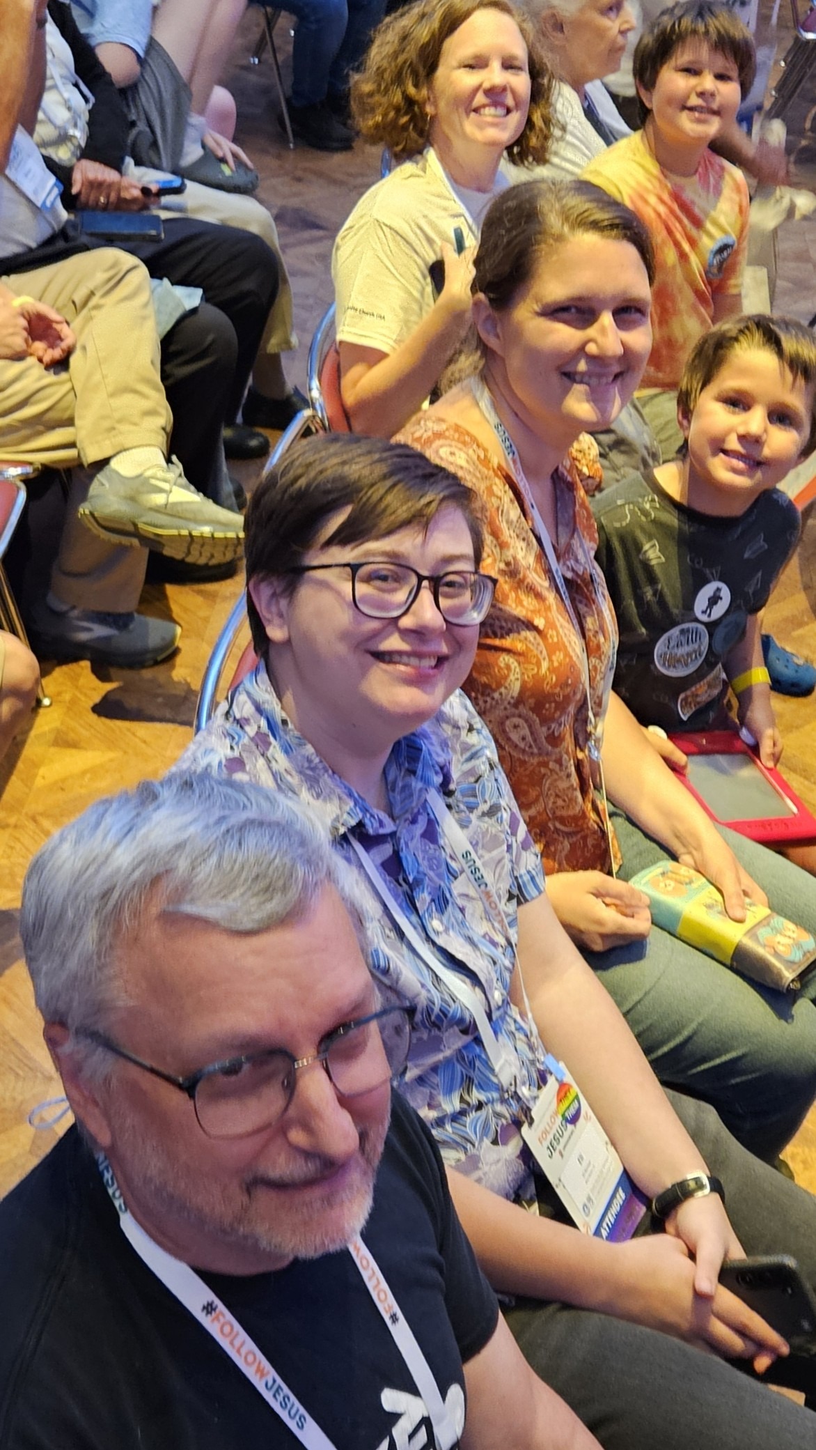 Four adults and two children smile at a convention. 