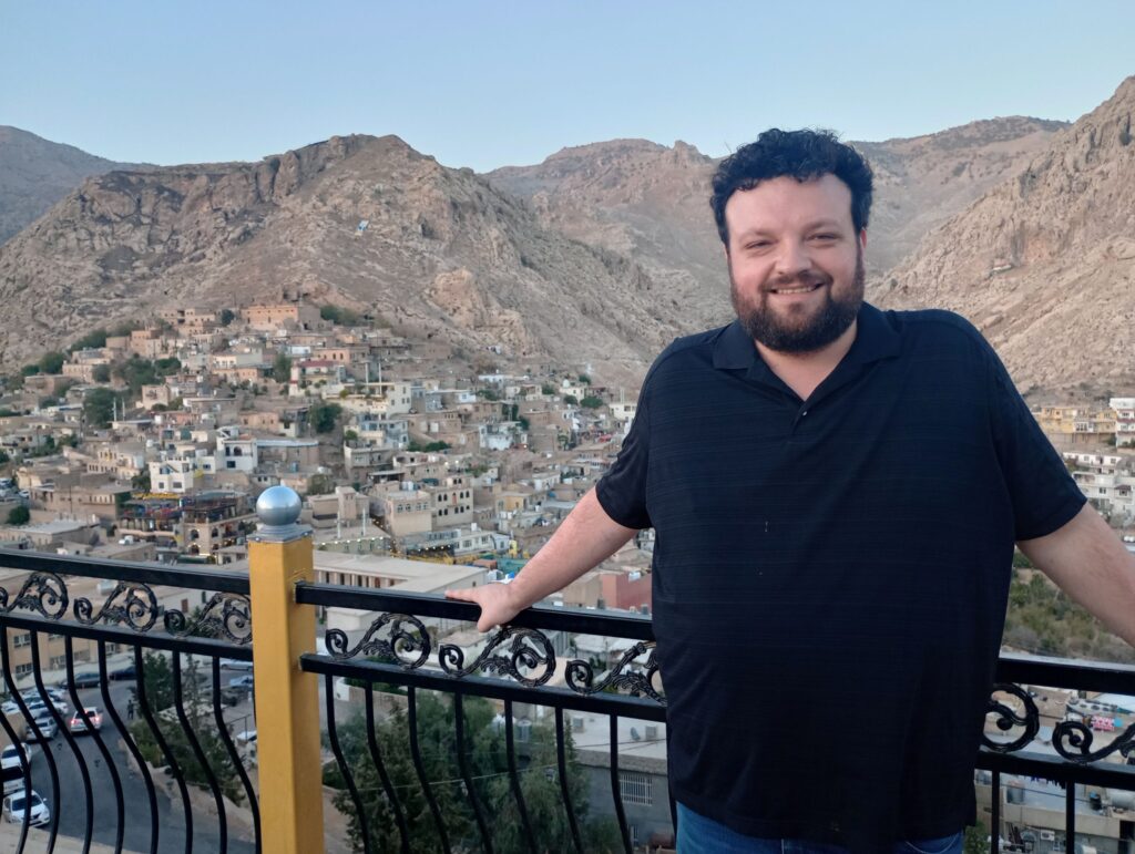 Man stands in front of mountainous view in the Middle East.   