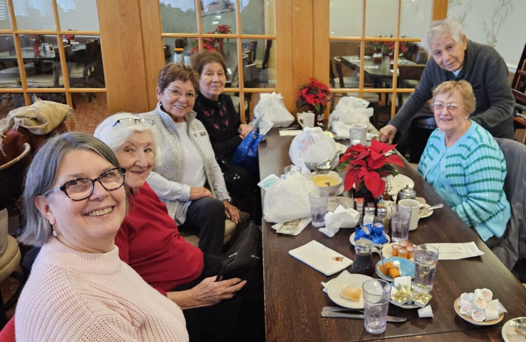 Group of smiling adults sit around a table in a restaurant.
