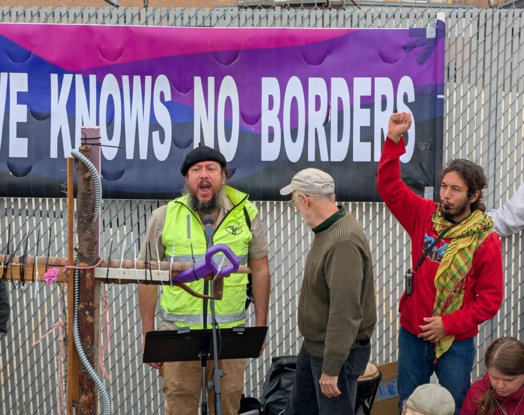 Three men protest in front of a detention facility.