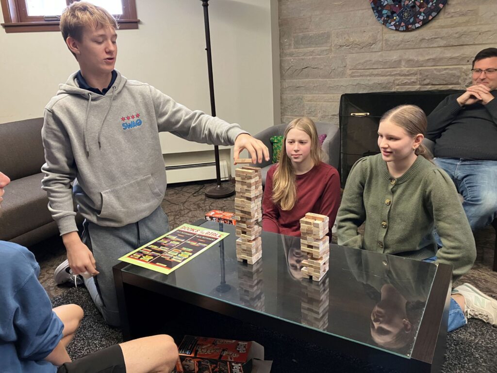 Group of teens play Jenga. 