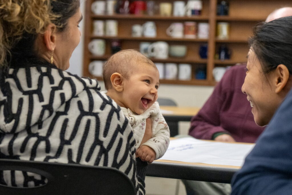 A baby smiles at a woman.