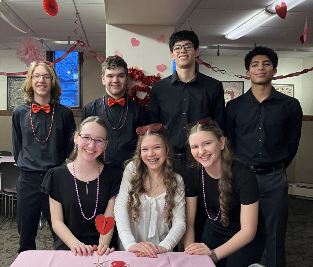 Group of smiling teenagers in a dining hall decorated for Valentine's Day.