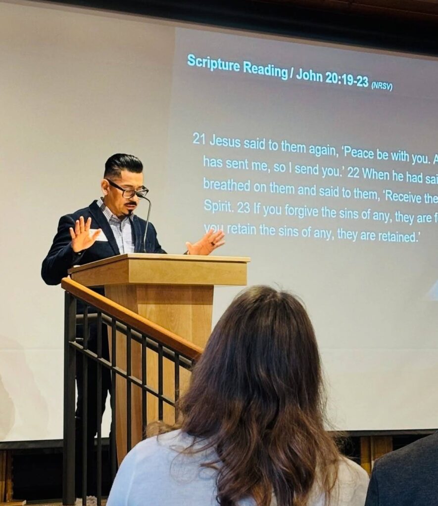 A man reads scripture at a pulpit.