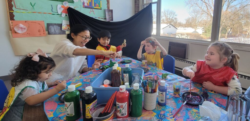 Children enjoy painting wooden figures around a table in a Sunday school classroom.