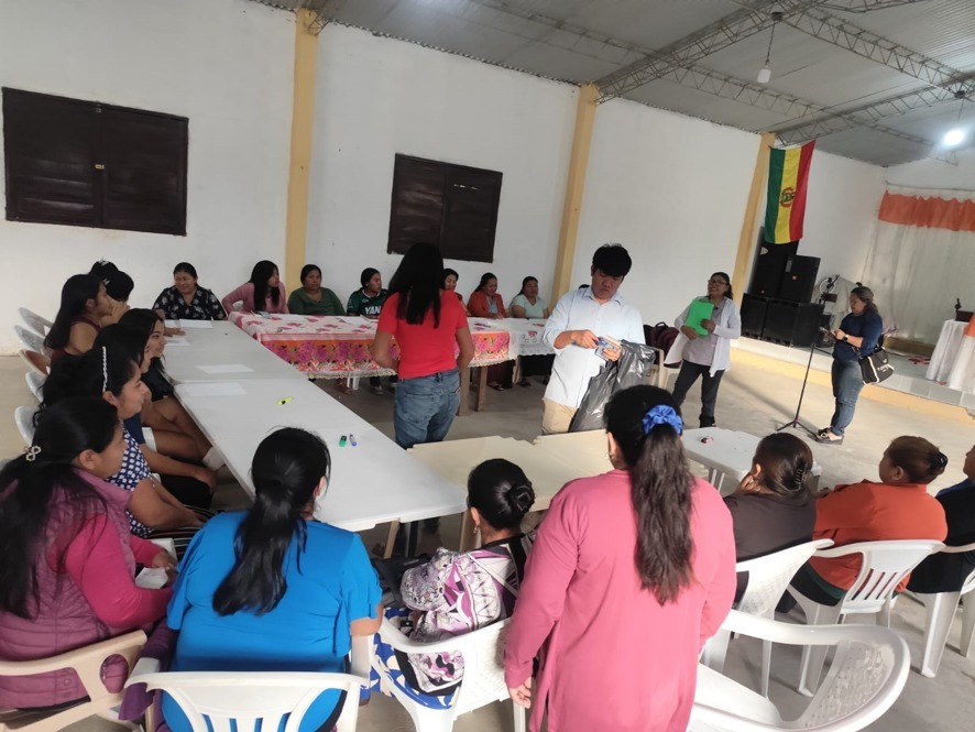 A group of women and children sit around tables at a family workshop.