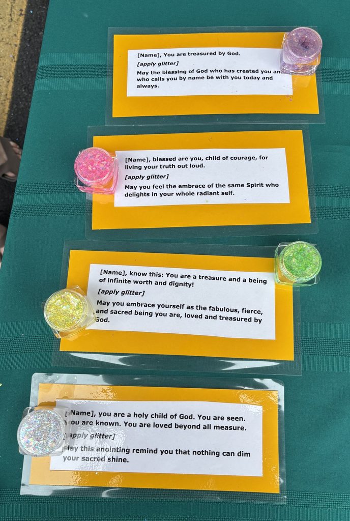 Four laminated blessings with small containers of glitter on a green tablecloth. 