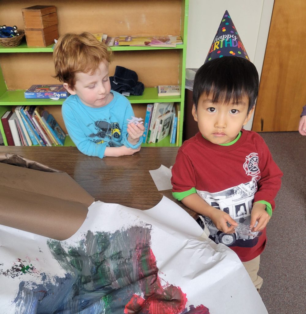 Two young boys by a painted art project in a Sunday school classroom. 