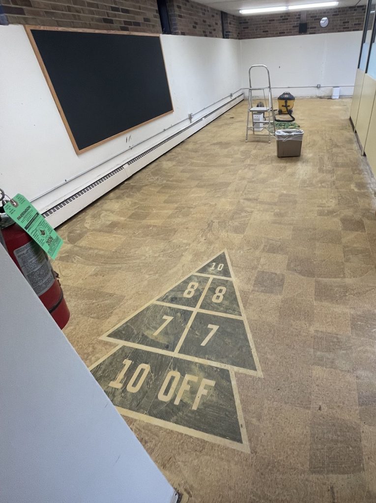 A painted shuffleboard scoring area on tile in a room cleared out for a renovation. 