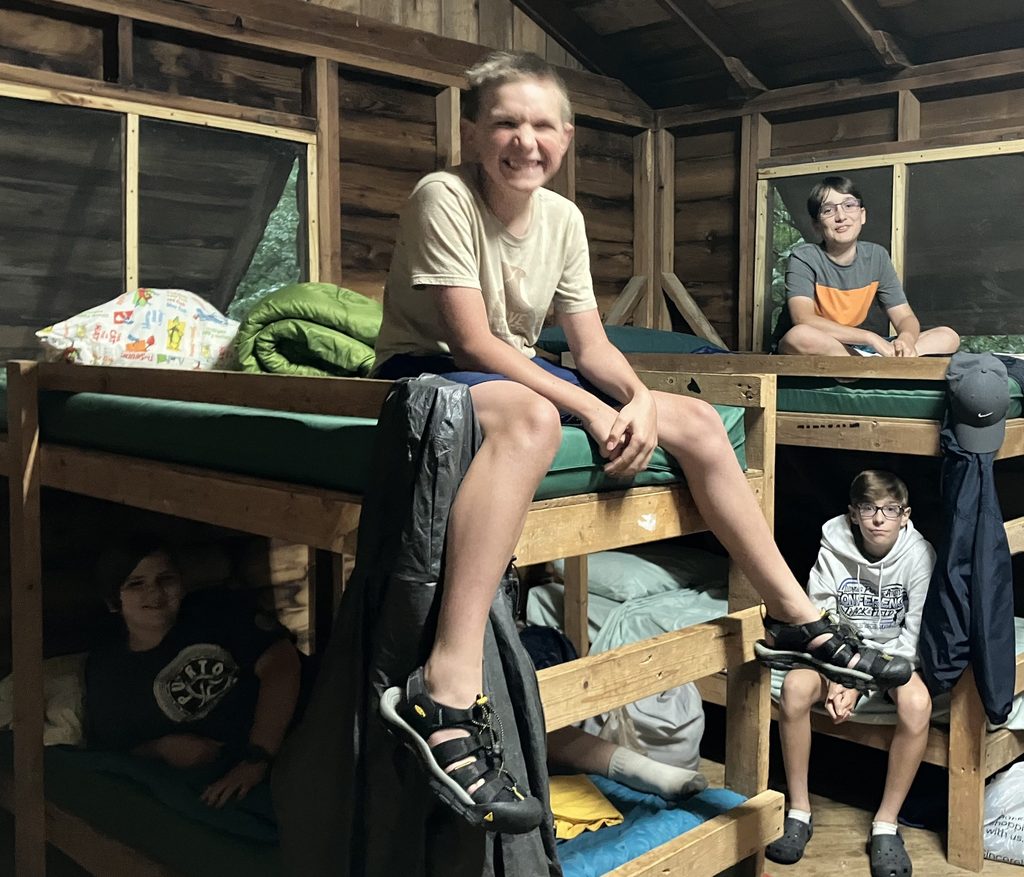 Boys on bunk beds inside a camp cabin. 