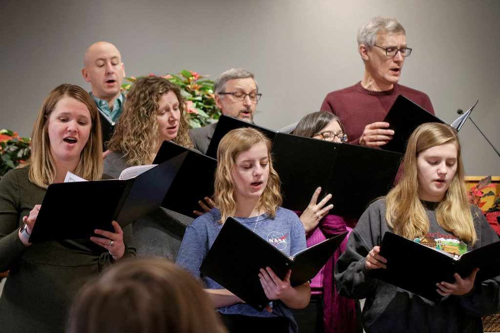 A mixed group of men and women sing in a choir.