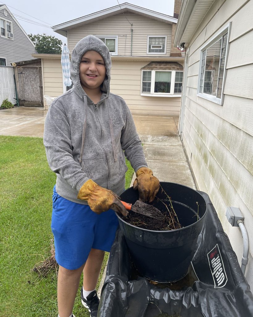 A smiling boy does yardwork